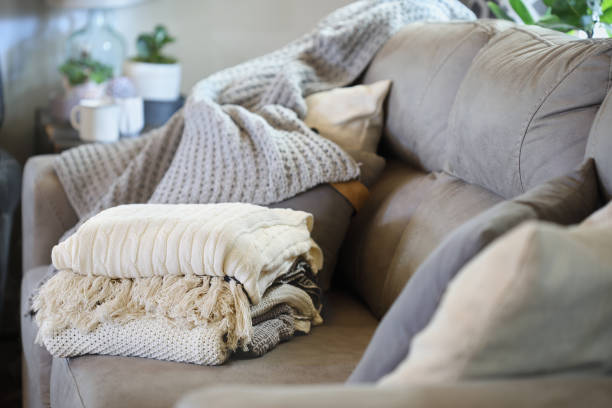 Cozy gray couch with a stack of folded knitted blankets, creating a warm inviting living space.