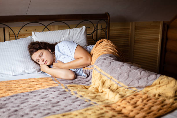 Woman resting under a warm, patterned blanket in bed.