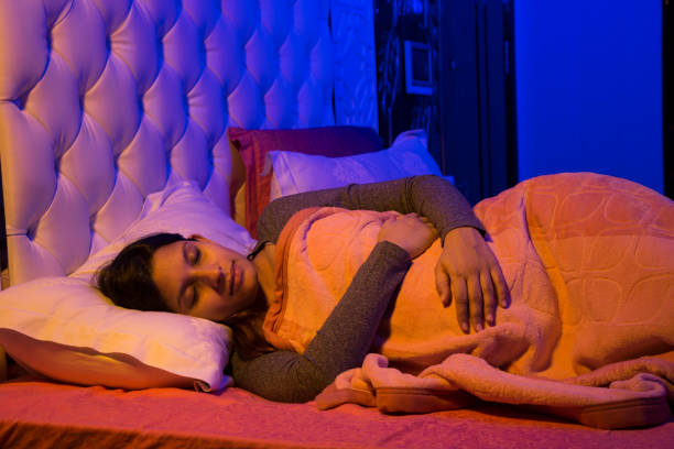 Woman peacefully sleeping under a warm orange blanket in a cozy bedroom setting.