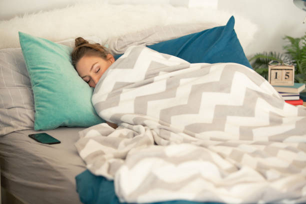 Person sleeping soundly under a comfortable grey and white chevron patterned blanket.