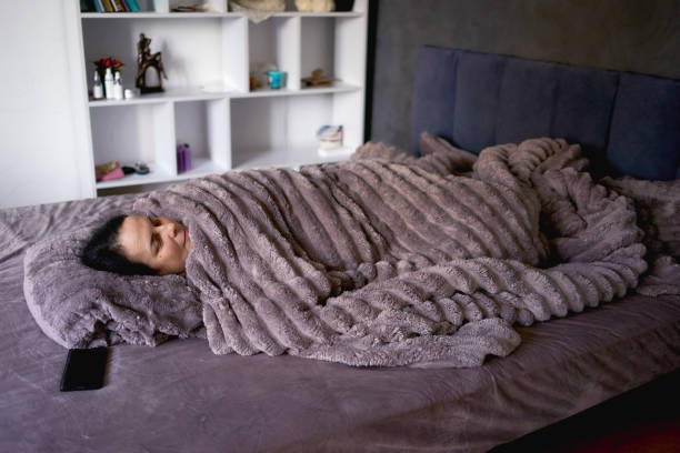 Person completely covered by a soft, warm ribbed blanket on a comfy bed.