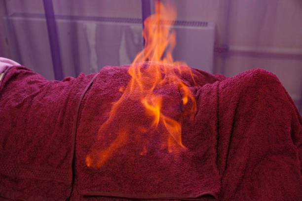 Person under a dark red blanket with flames burning on top for therapy.