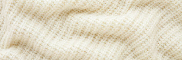Close-up of a soft, cream-colored knitted wool blanket texture.