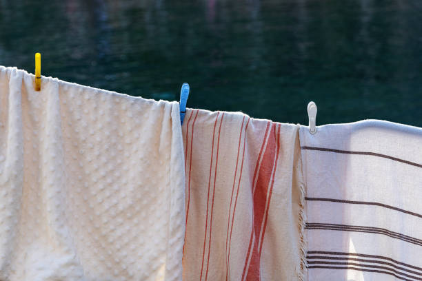 Towels and small striped blankets hanging on a clothesline to dry outdoors.