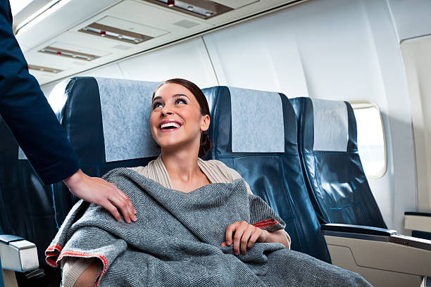 Smiling woman receiving a grey blanket from a flight attendant.