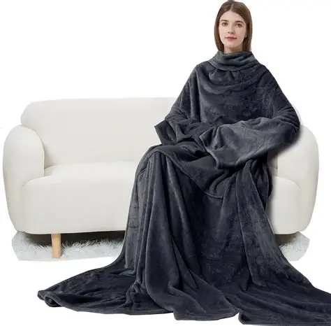 Woman wearing a soft dark grey sleeved blanket, sitting comfortably on a white sofa.