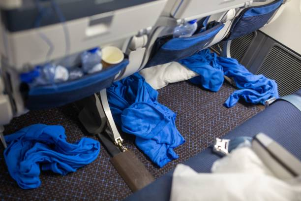 Messy airplane cabin floor with several blue blankets and water bottles.