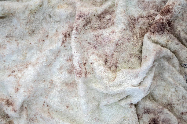 Close-up of a dirty white woven blanket with reddish-brown stains, needing a clean.